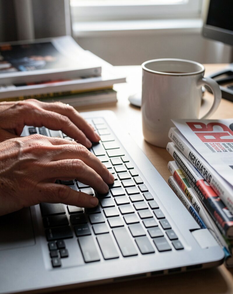 A lone developer at a home work table late at night, monitor glow on a wall of pinned notes, a kettle steaming beside.